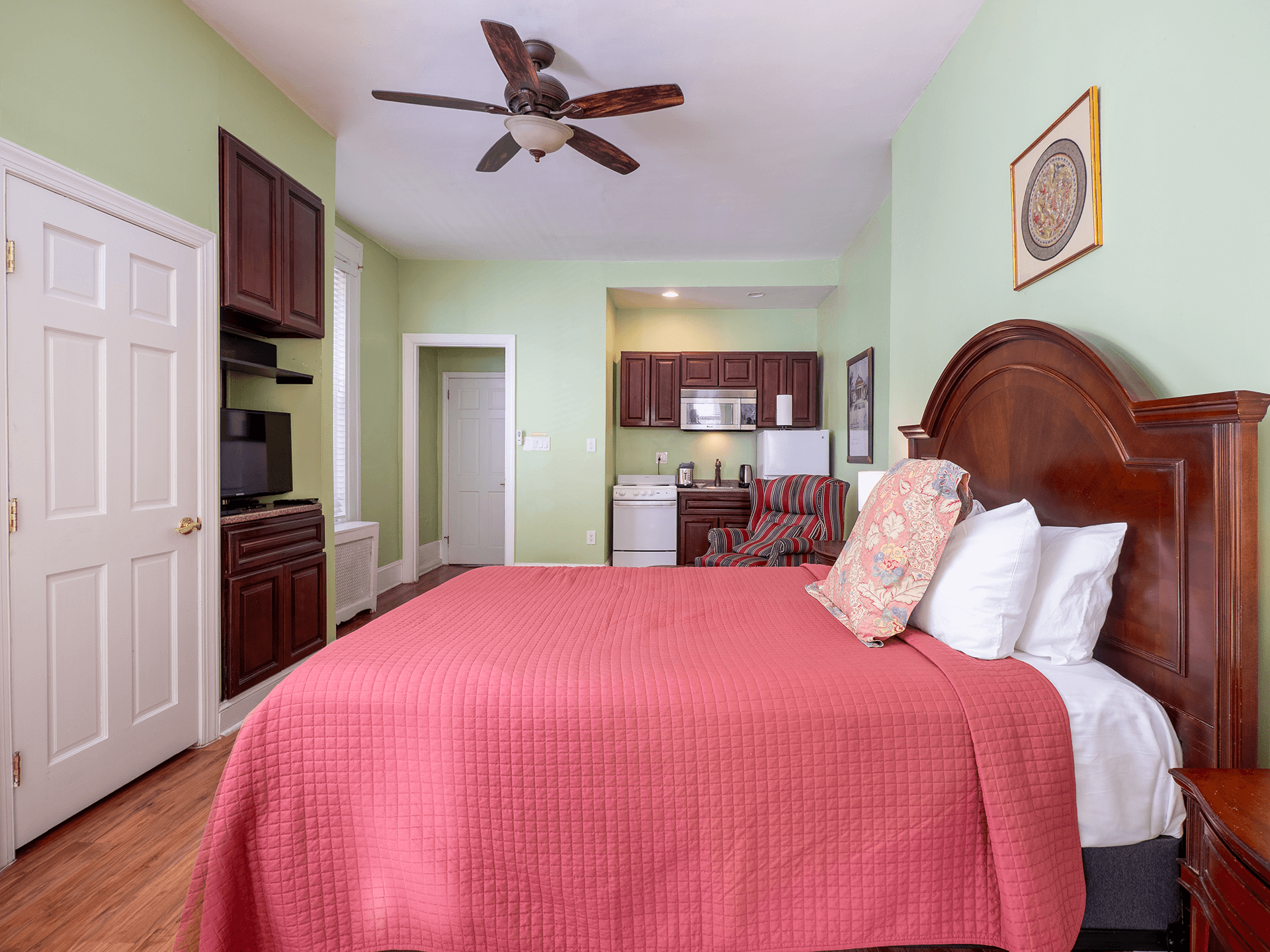 Brightly colored studio apartment featuring a king-size bed, kitchenette, and comfortable seating area.